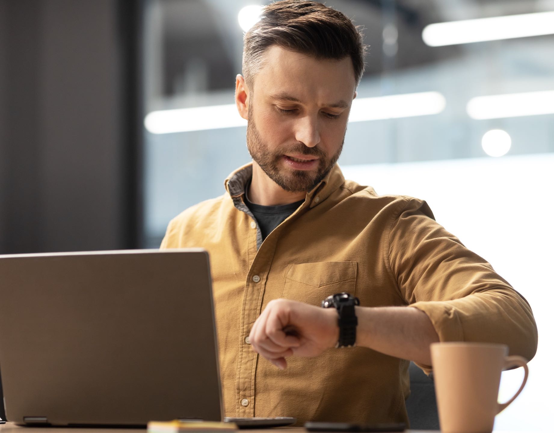 A person looking at their watch in an office setting, symbolizing the frustration of waiting for tech support.